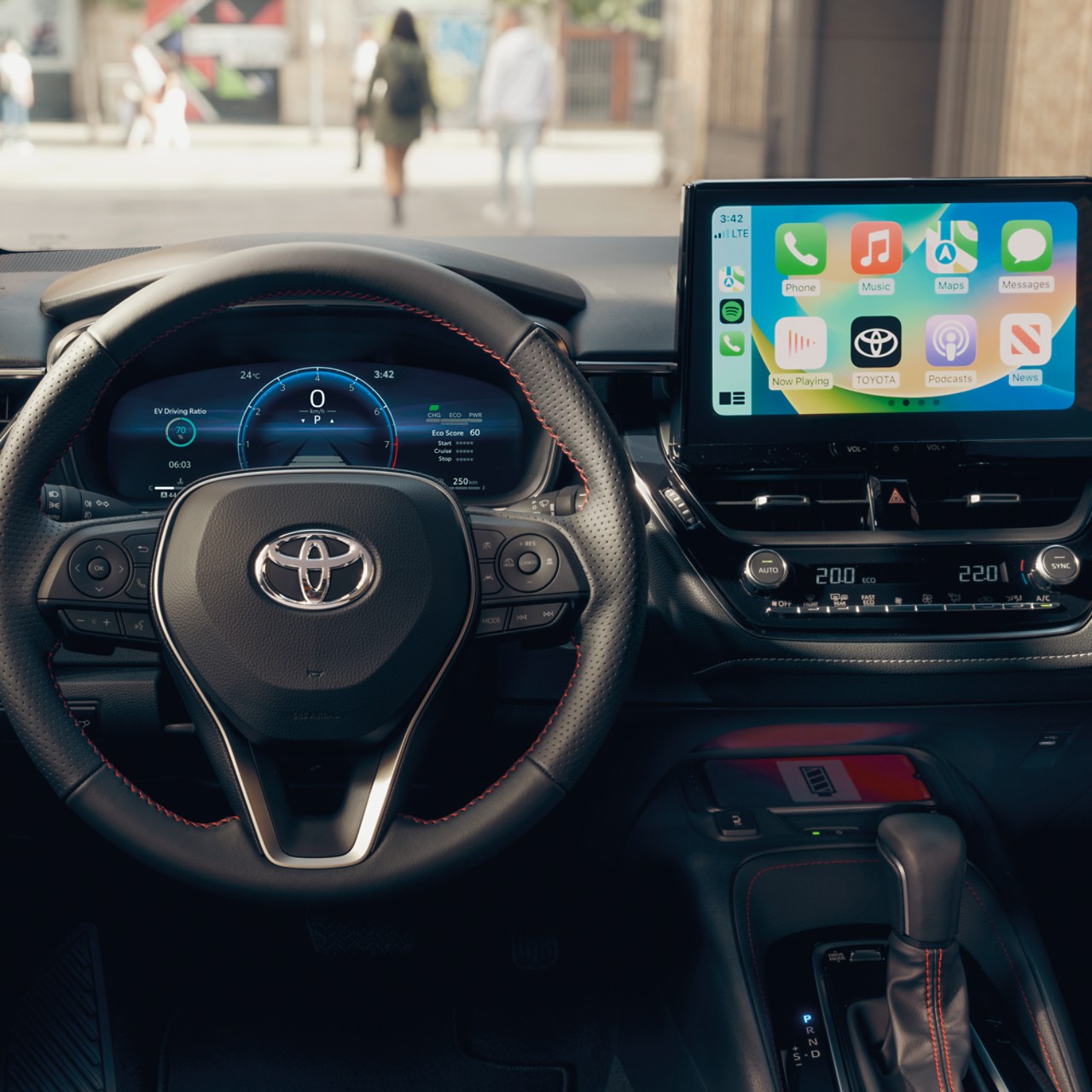 Uno schermo tattile multimediale mostra la schermata home di Apple CarPlay in un veicolo Toyota con plancia degli strumenti nera.